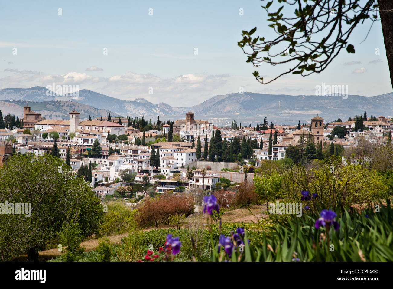 The whitewashed houses of the city of Granada rise among flowers, trees, and mountains of the Andalusia region of southern Spain Stock Photo