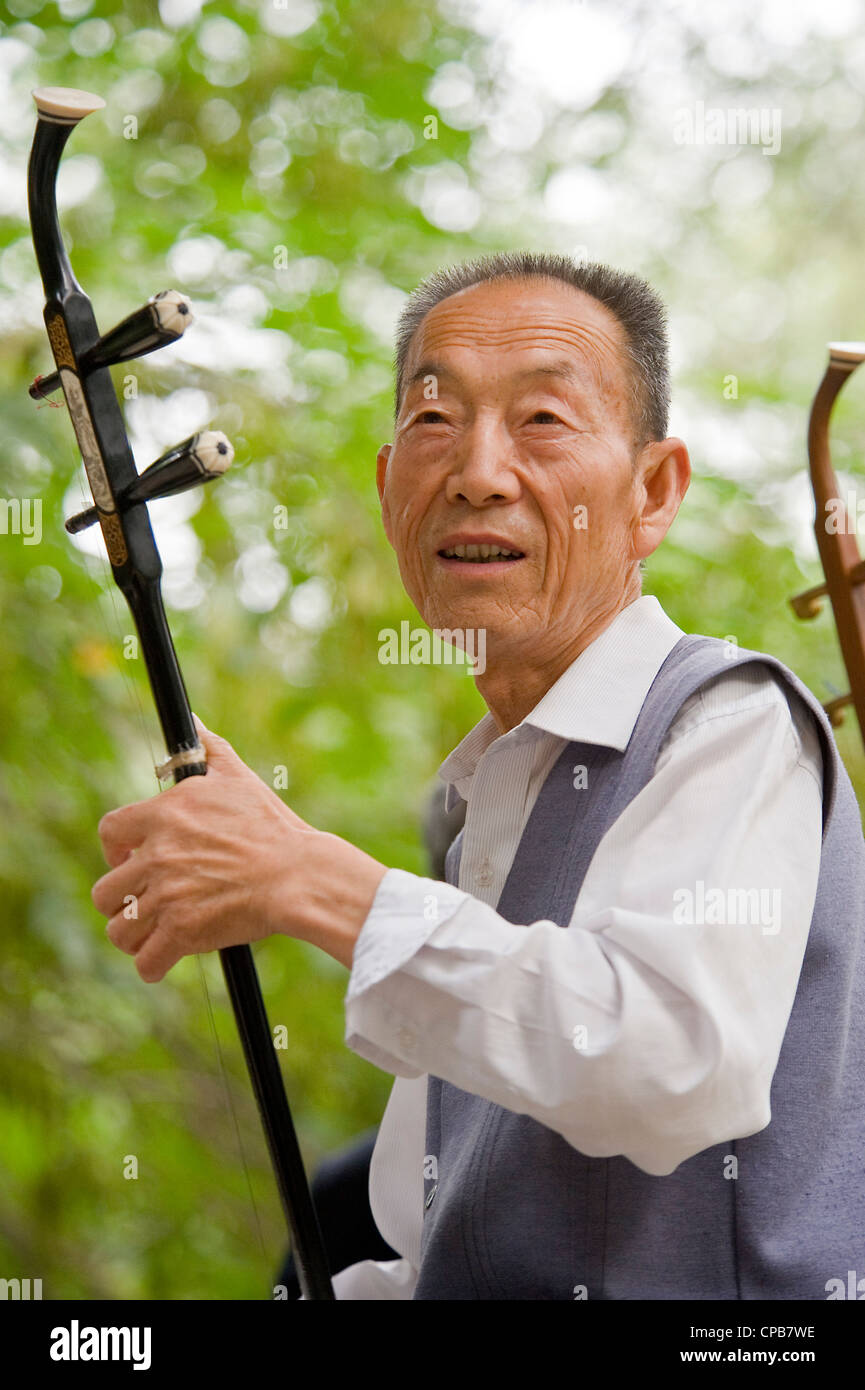 A Chinese musician playing the traditional Chinese instument, Erhu - Chinese violin, early morning at a park in Pingliang. Stock Photo