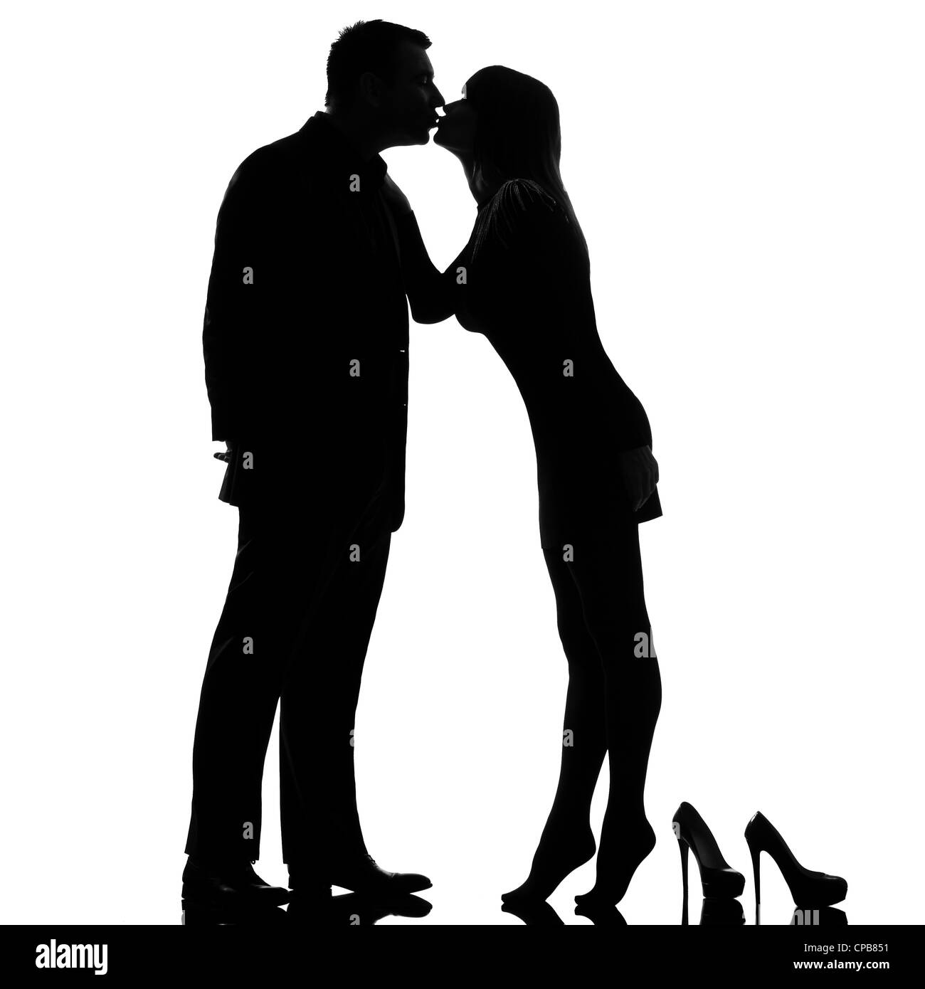 one caucasian couple kissing man and woman barefoot tiptoe full length in studio silhouette isolated on white background Stock Photo