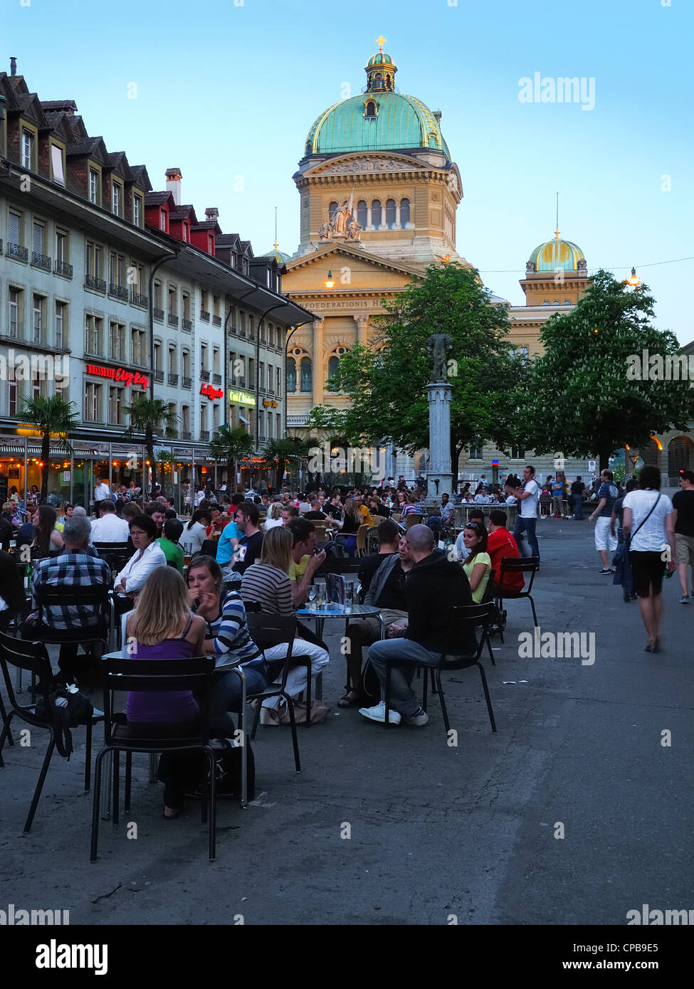 People enjoy a warm spring evening at the Baerenplatz (Bear Plaza) in front of the Swiss Capitol, city of Bern, Switzerland. Stock Photo