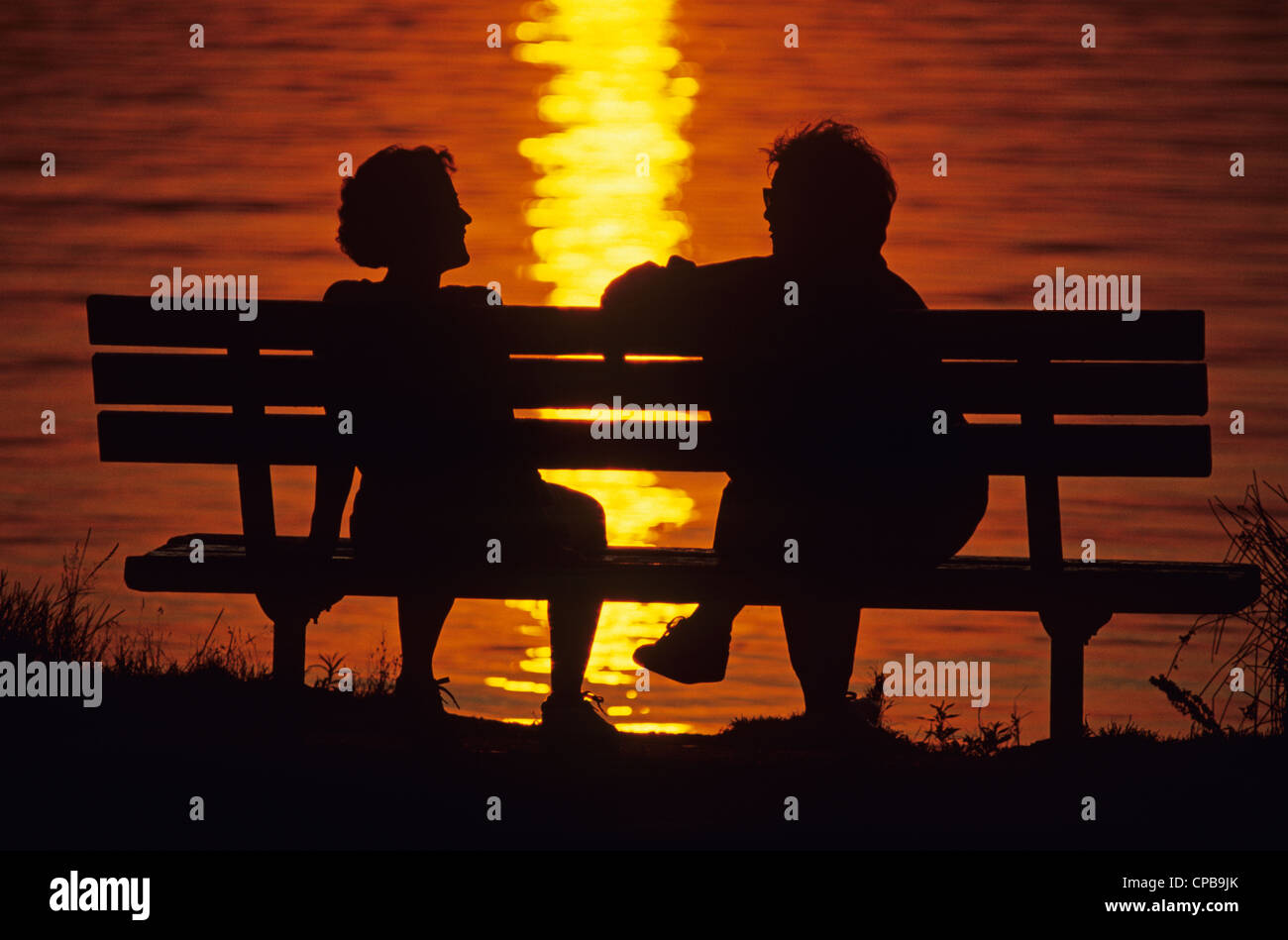 Sunset at Greenlake with silhouetted couple on park bench sitting and ...