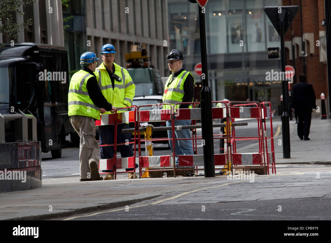 Roadworks, road works, workmen contractors standing around hole in road, London Stock Photo