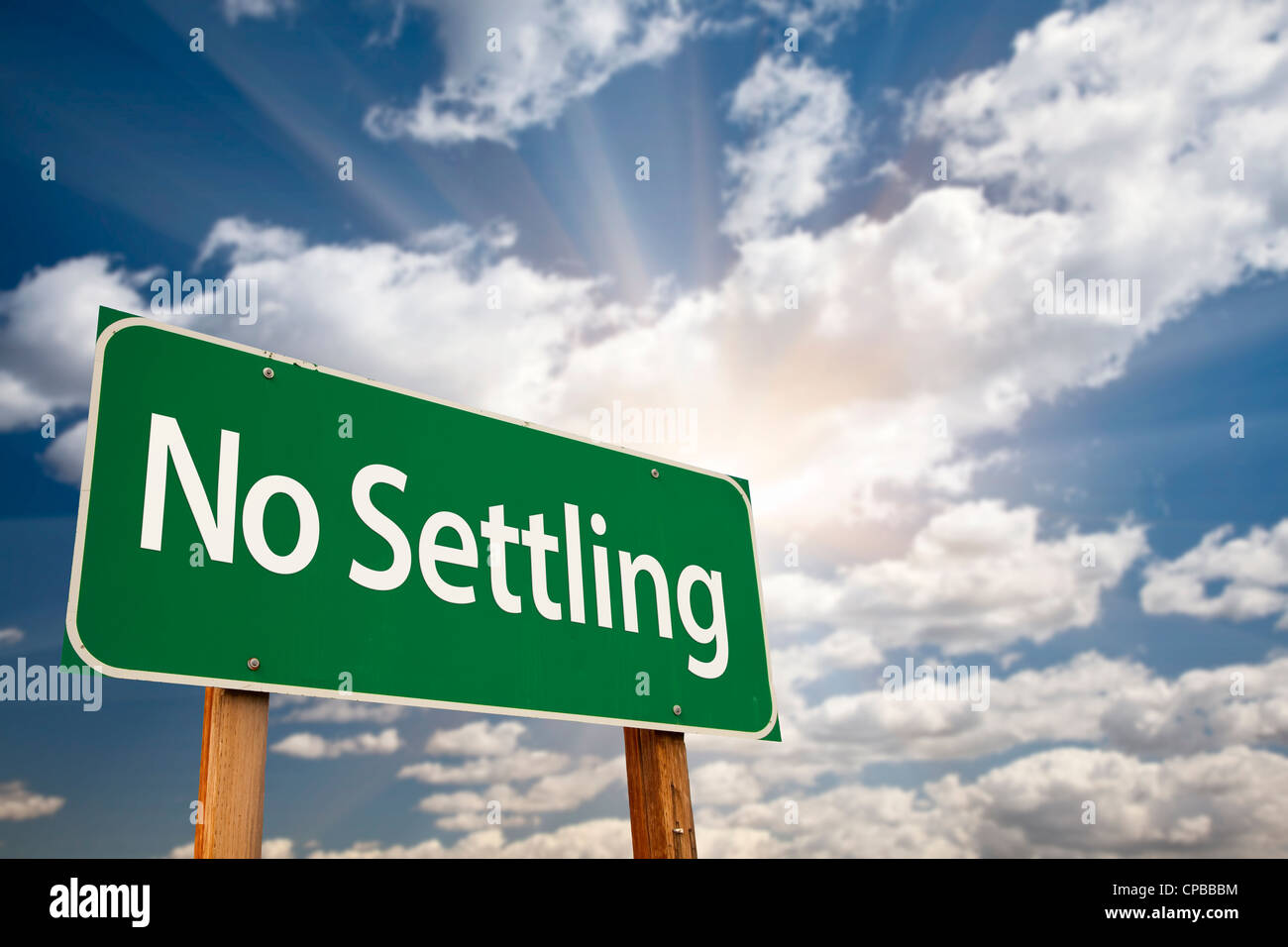 No Settling Green Road Sign with Dramatic Clouds, Sun Rays and Sky. Stock Photo