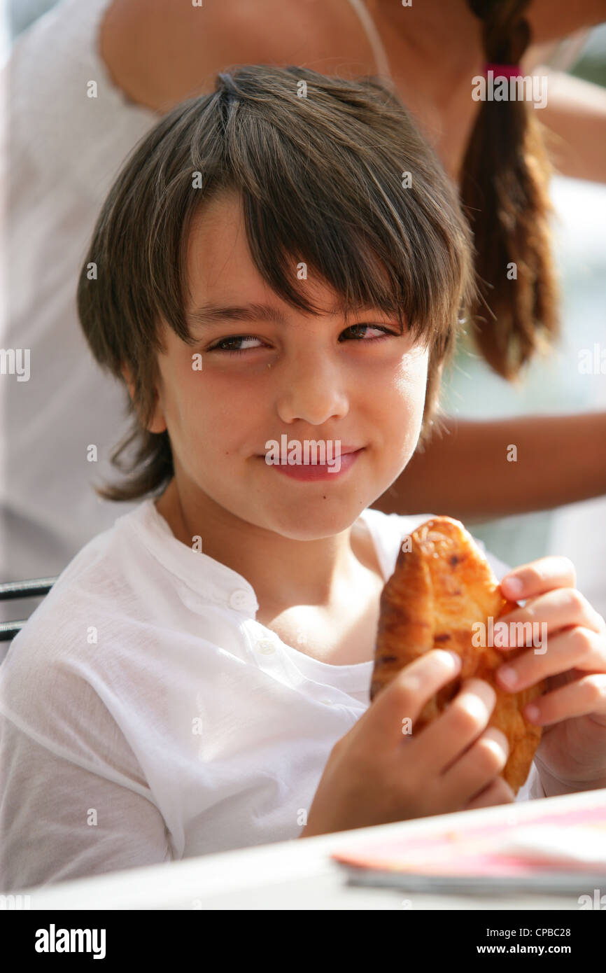 Boy eating a croissant Stock Photo