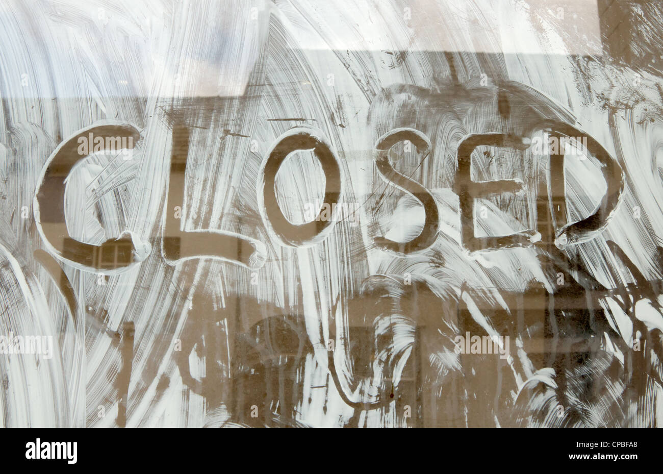 Closed written in the white paint of a shop window. Stock Photo