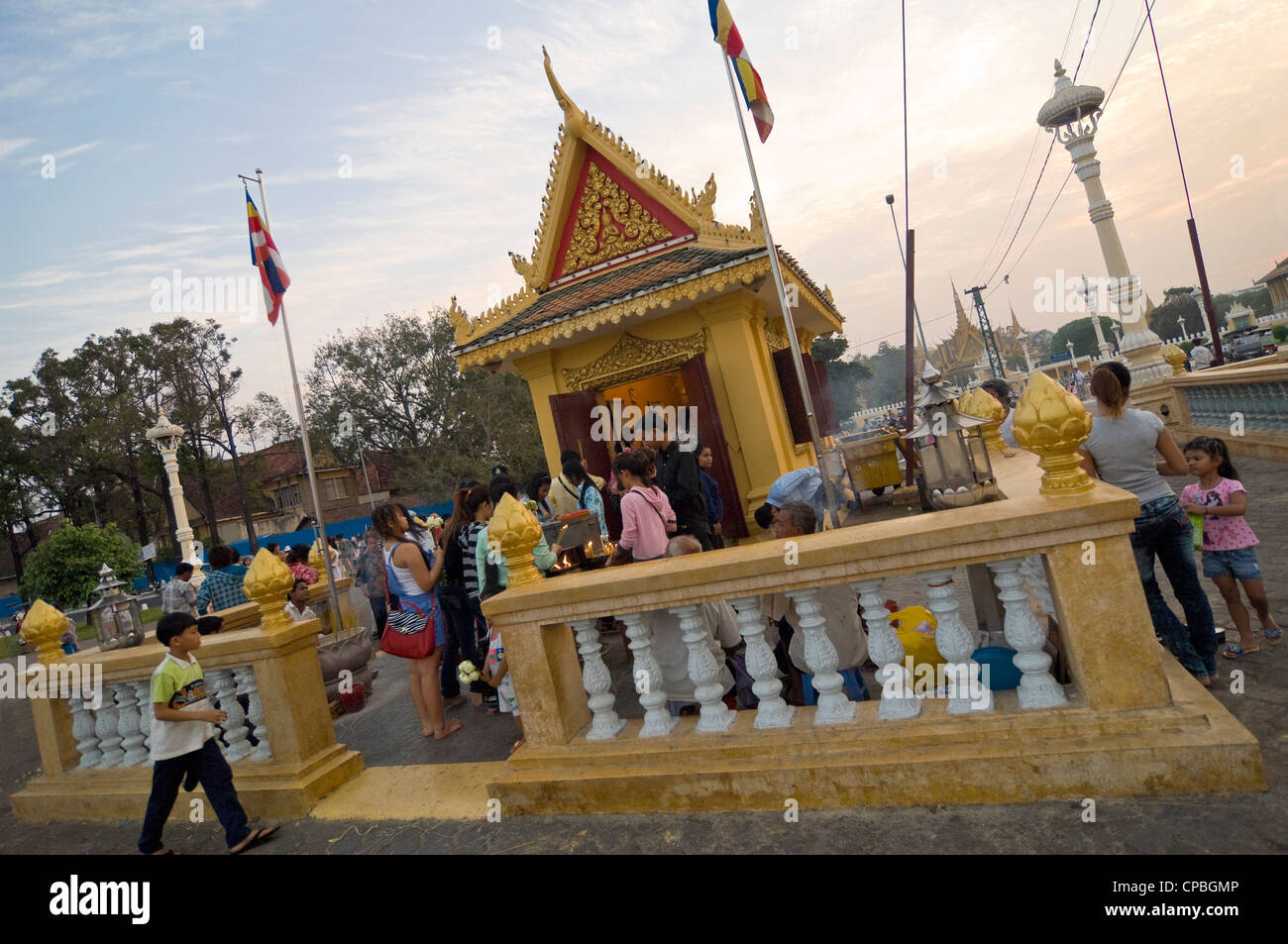 Horizontal view of a shrine on the Tonle Sap river front with many Cambodians praying and lighting joss-sticks. Stock Photo