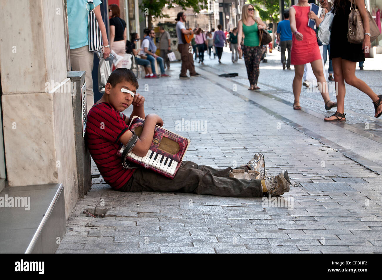 Kid begging with accordion on street in Athens, Greece Stock Photo