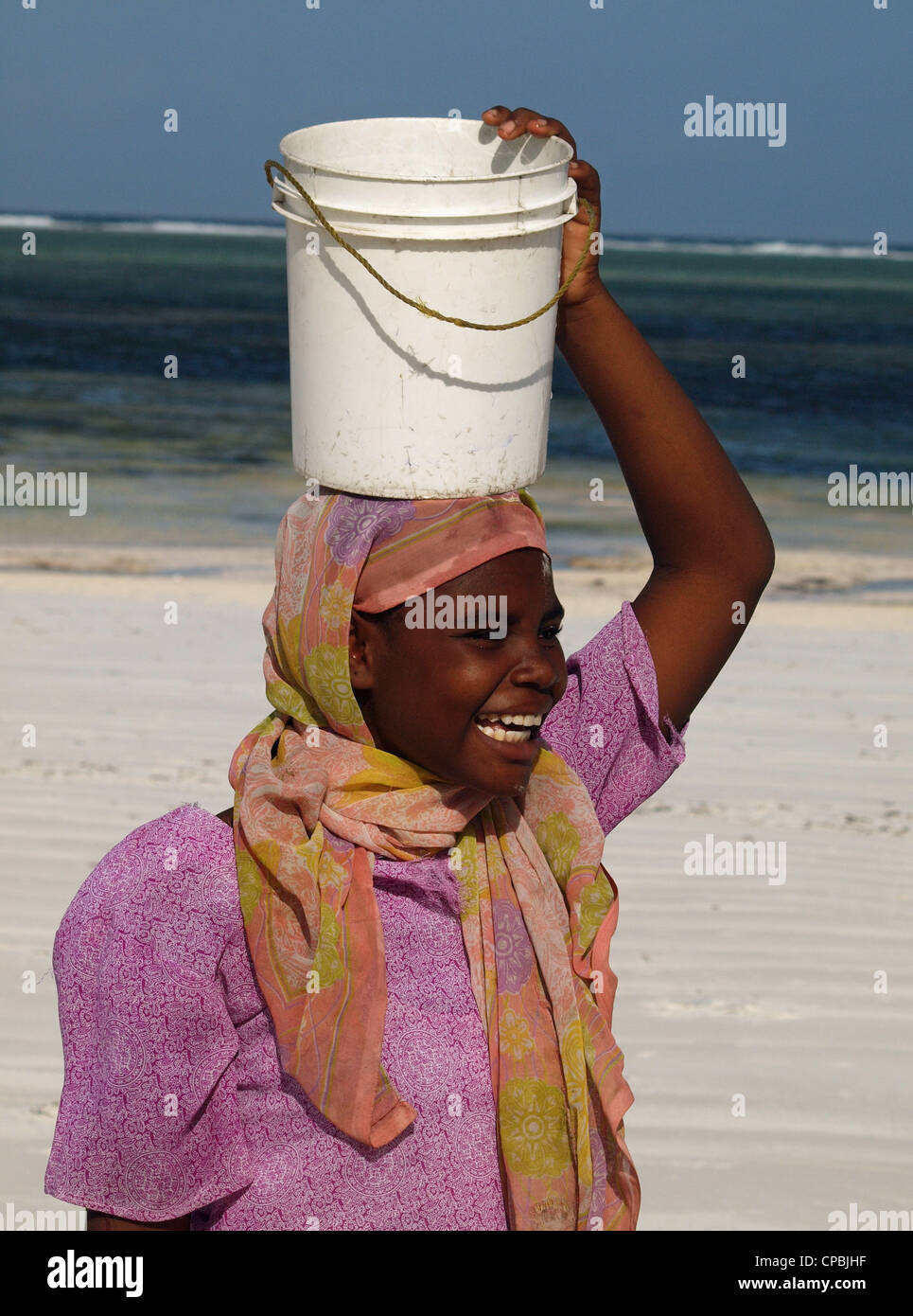 Local Swahili Woman In Colourful Traditional Costume Laughing On A White Sandy Beach In Zanzibar 