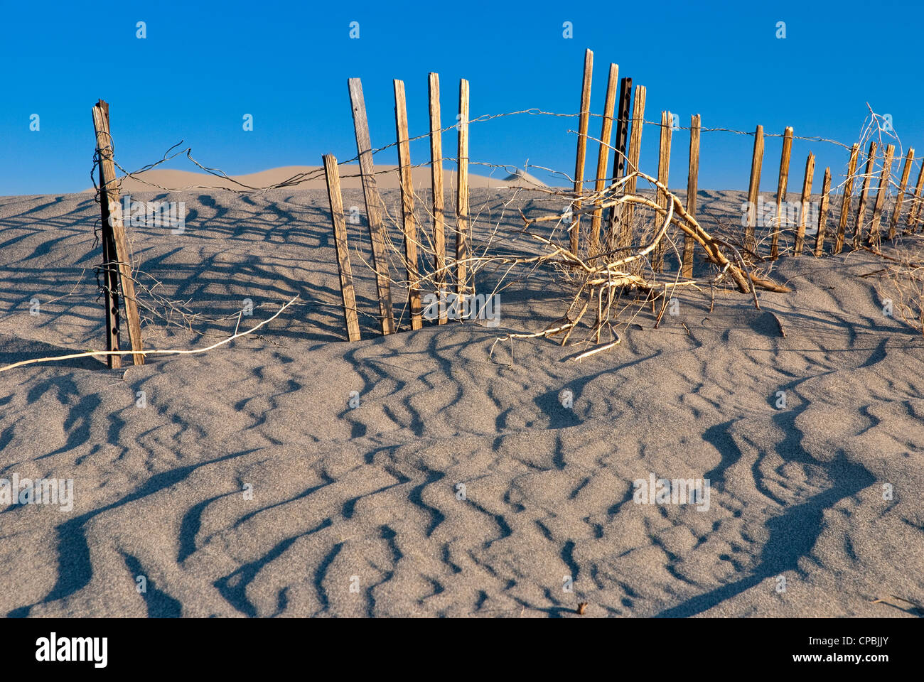 Wind blown sand has buried an old wooden fence Stock Photo