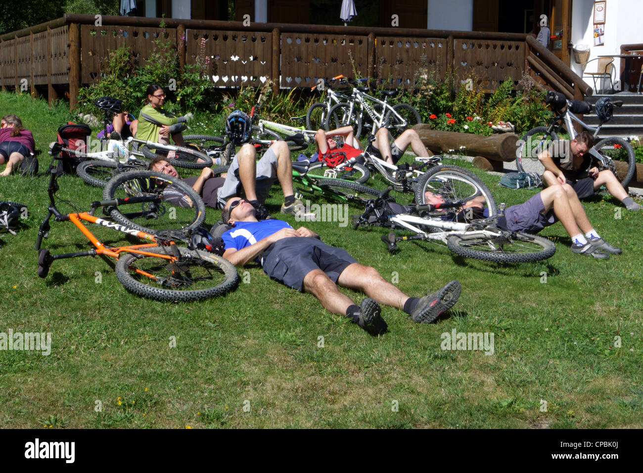 Tired cyclists relaxing on the grass on the mountain bike Tour de Mont Blanc Stock Photo