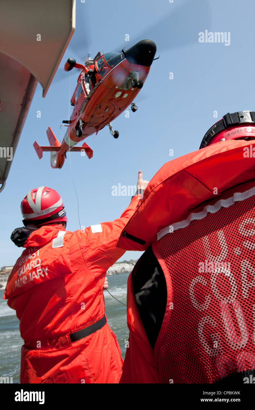 A United States Coast Guard HH-65C Dolphin helicopter works with the crew of a Coast Guard Auxiliary vessel. Stock Photo