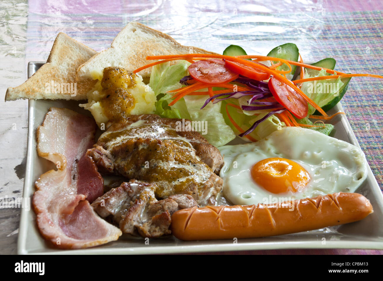Steak pork, bacon, fried egg, sausage, bread and salad. Stock Photo