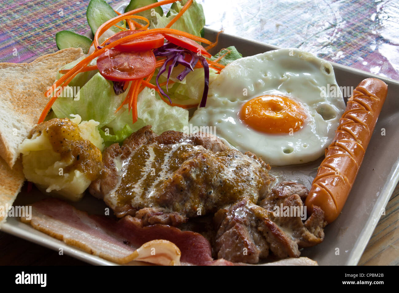 Steak pork, bacon, fried egg, sausage, bread and salad. Stock Photo