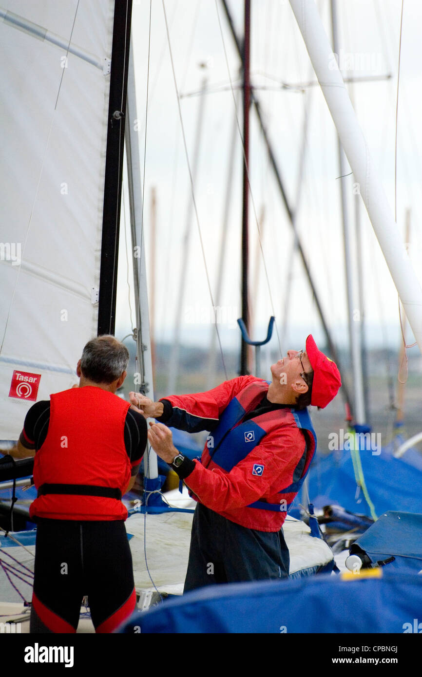 Two men prepare a sailing dinghy, Whitstable Yacht Club Kent, England