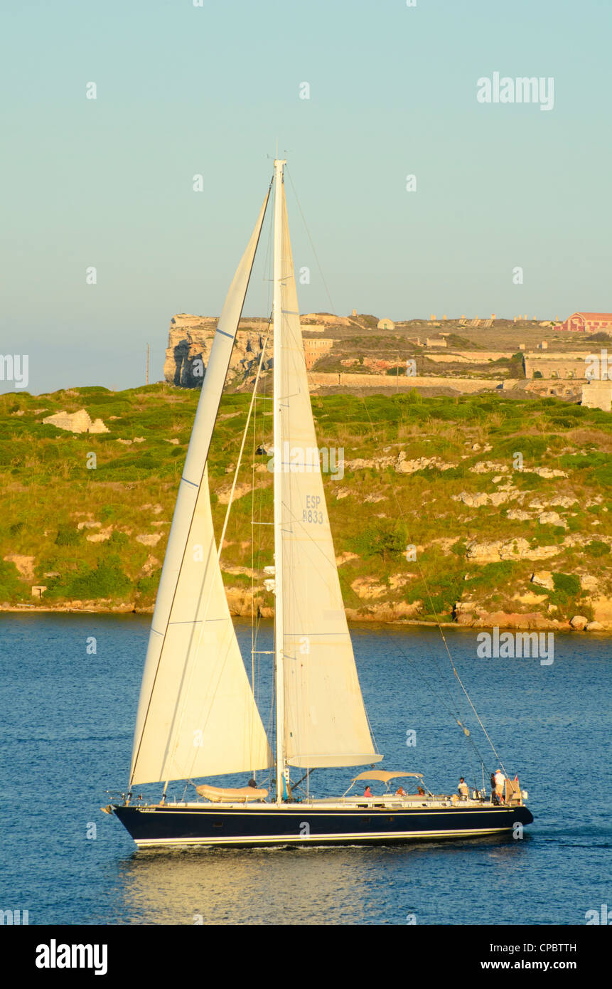 Yacht in the great natural harbour of Maó (Mahón) on Menorca in the Balearic islands, Spain Fortalesa de la Mola behind Stock Photo