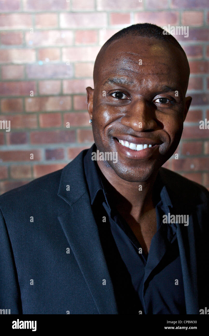 Portrait of a black man in a blue suit against a brick wall background ...