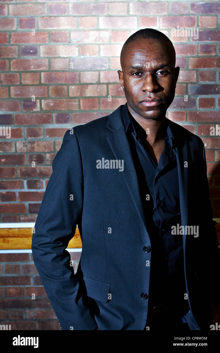 Portrait of a black man in a blue suit against a brick wall background ...