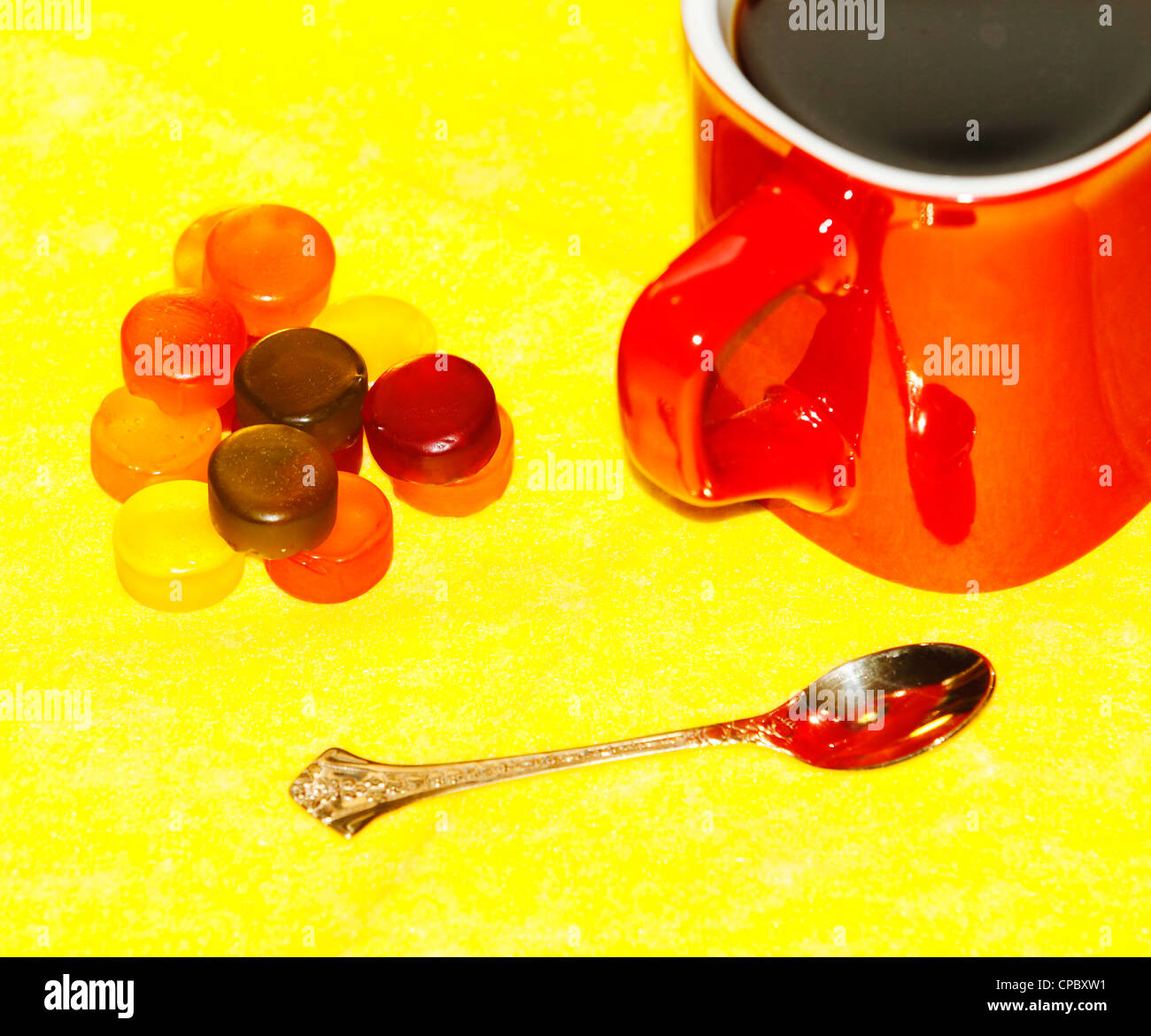 cup of coffee in the red, tasty, pretty sweet, golden spoon on a yellow background Stock Photo