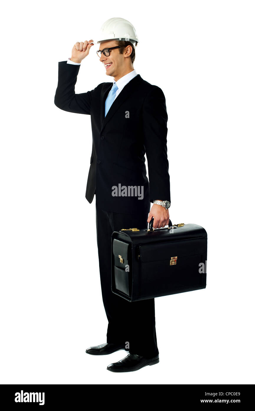 Smiling architect holding his hard hat and briefcase. Looking away Stock Photo