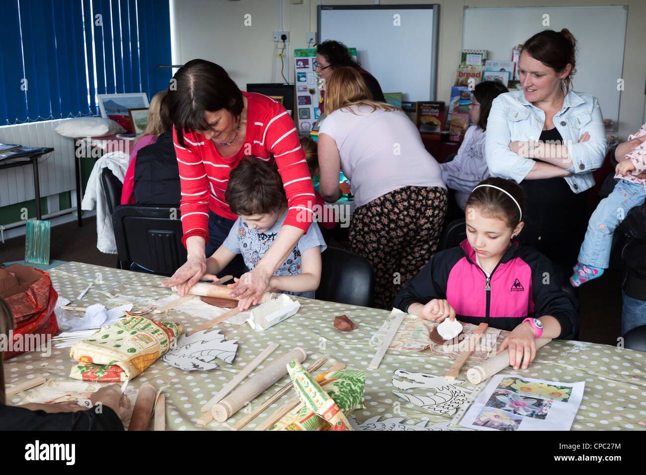 Children working with clay in art class with adult helpers, UK Stock Photo