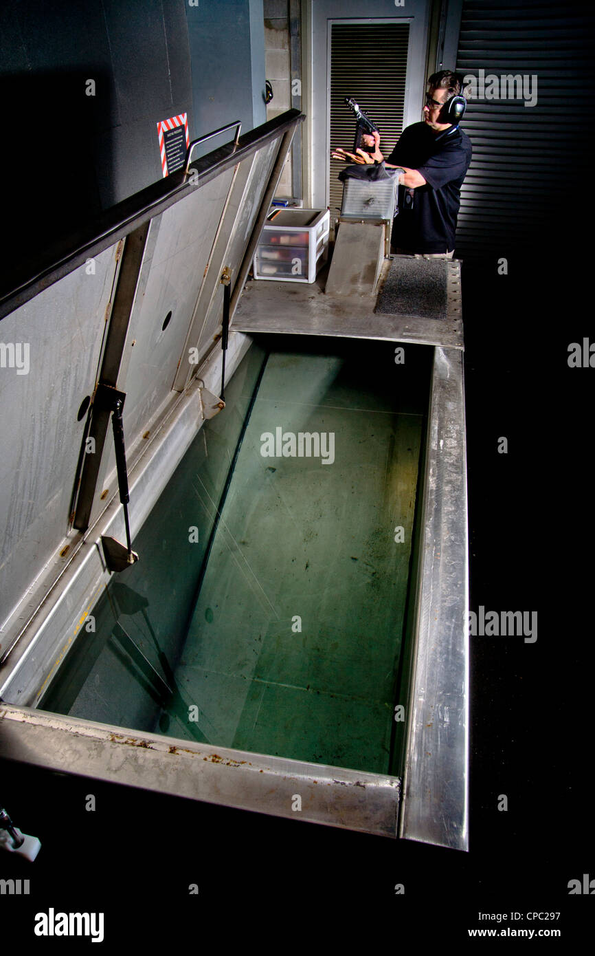 A Santa Ana, CA, police weapons specialist prepares to fire a test bullet from a TEC-9 machine gun into a water-filled tank. Stock Photo