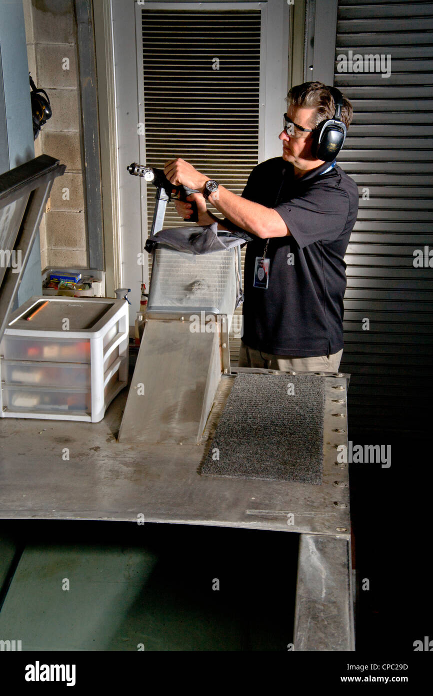 A Santa Ana, CA, police weapons specialist prepares to fire a test bullet from a TEC-9 machine gun into a water-filled tank. Stock Photo