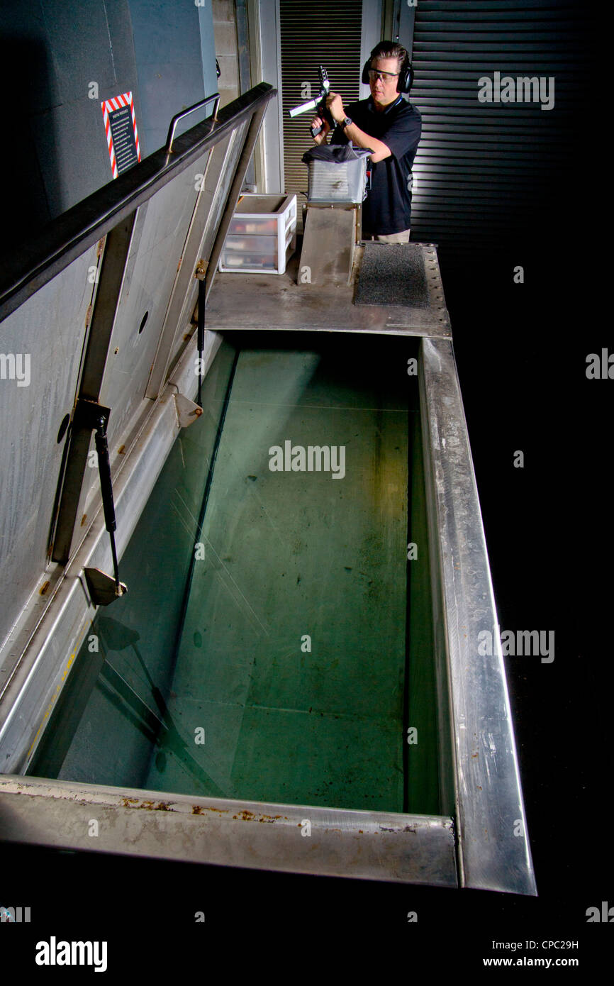 A Santa Ana, CA, police weapons specialist prepares to fire a test bullet from a TEC-9 machine gun into a water-filled tank. Stock Photo