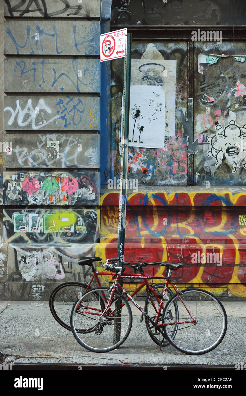 Bike's padlocked to a street sign in a graffitied street Soho, New York Stock Photo