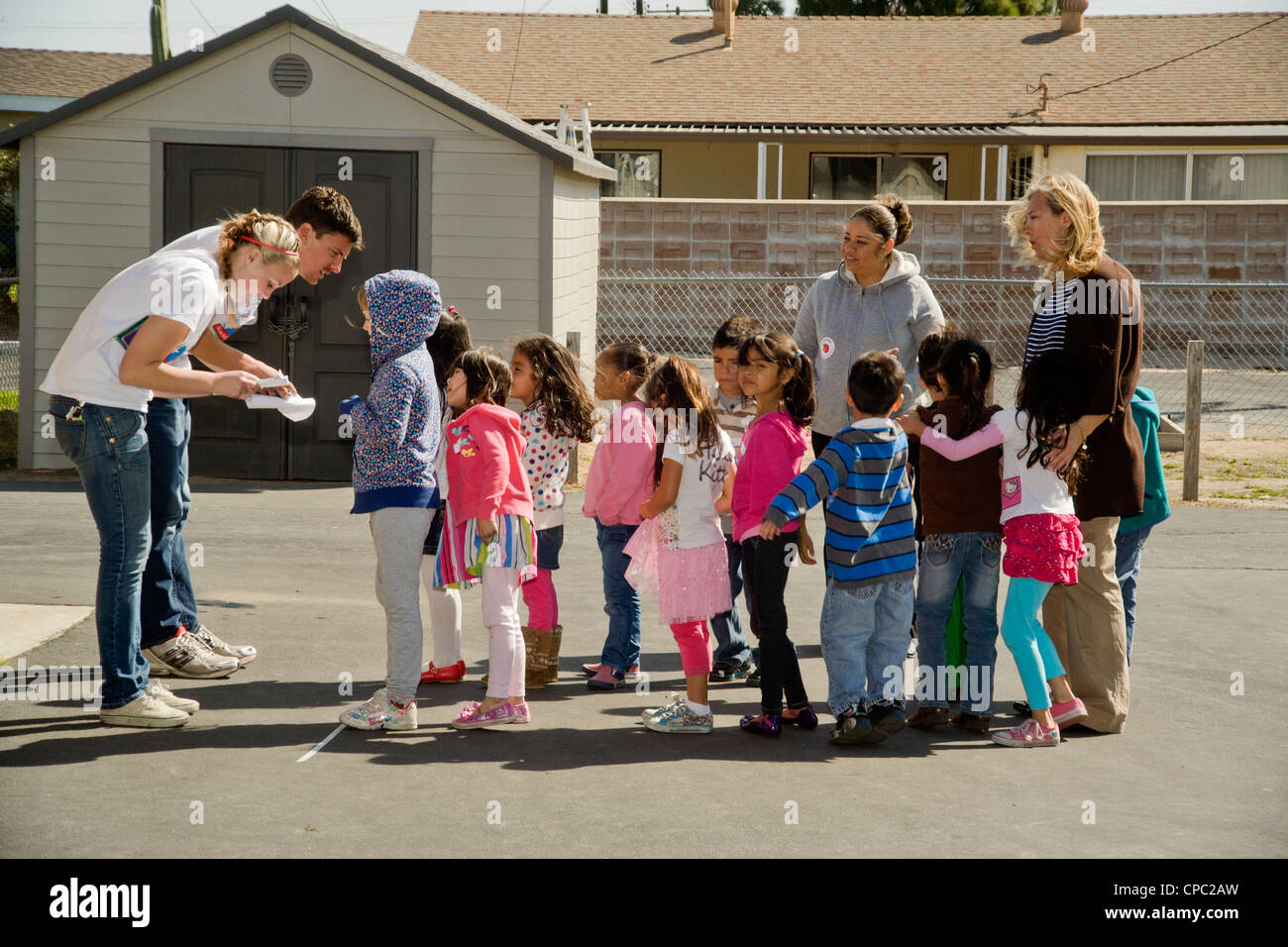 Volunteer teachers quiz a line of Hispanic children about their literary tastes in an outdoor 'Dr. Seuss Annual Literacy Fair' . Stock Photo