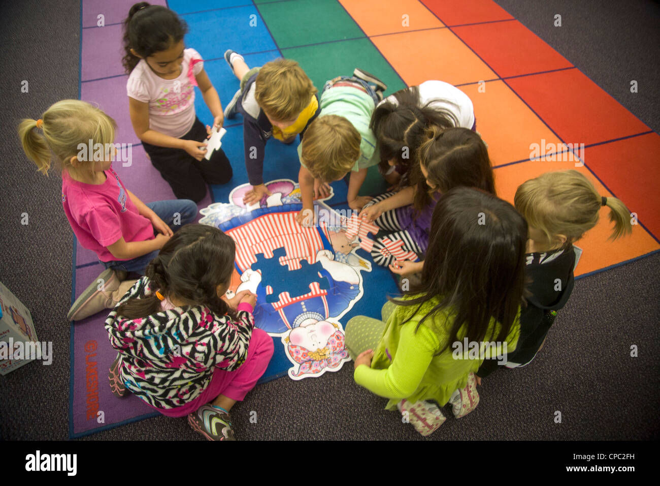 On a classroom floor, a group of kindergarten children collaborate to