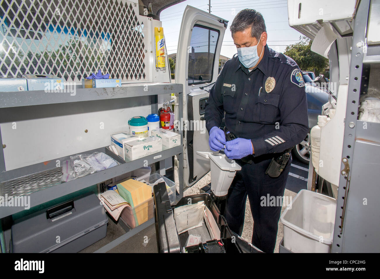 In his official van in Santa Ana, CA, a Hispanic police officer prepares a scent transfer unit at a crime scene. Stock Photo