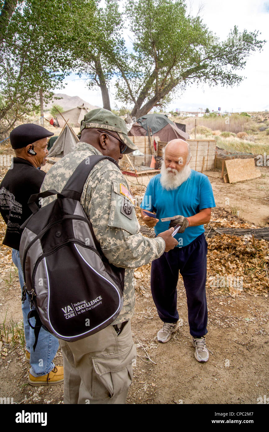 An African-American U.S. Army reservist offers a homeless military veteran information on Veterans Administration medical care. Stock Photo