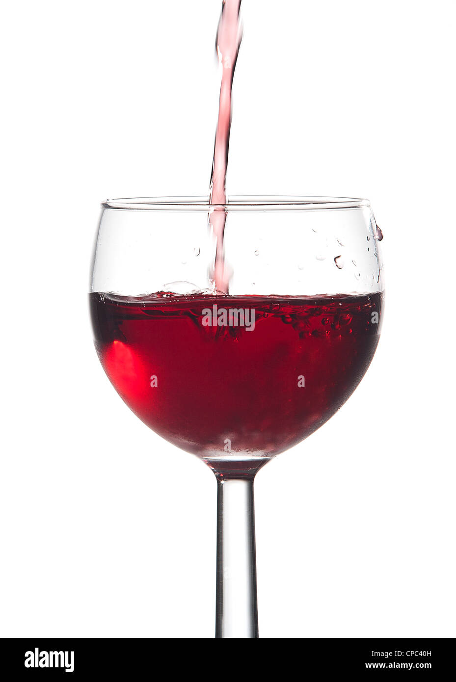 Bubbles from pouring red wine into a glass against a white background. Stock Photo