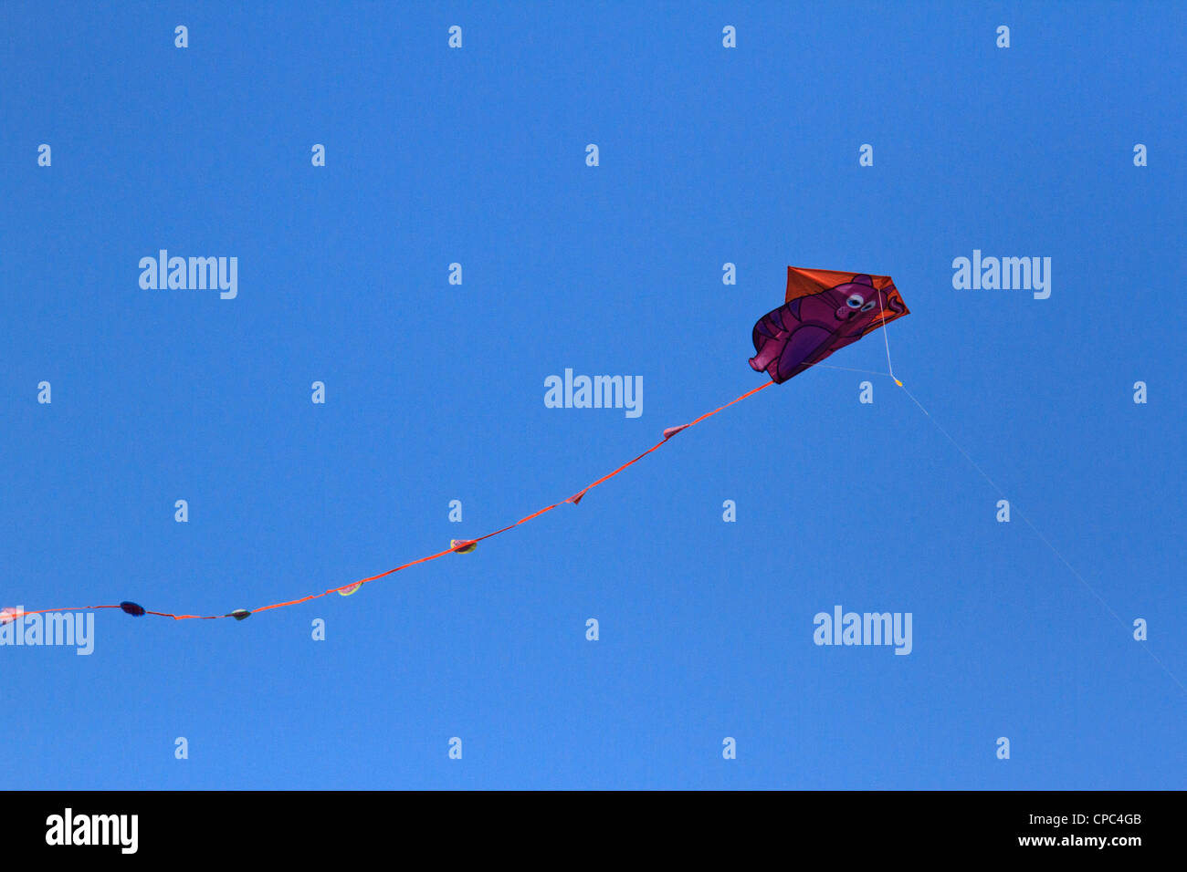 Kite flying against a clear, blue, cloudless sky. Stock Photo