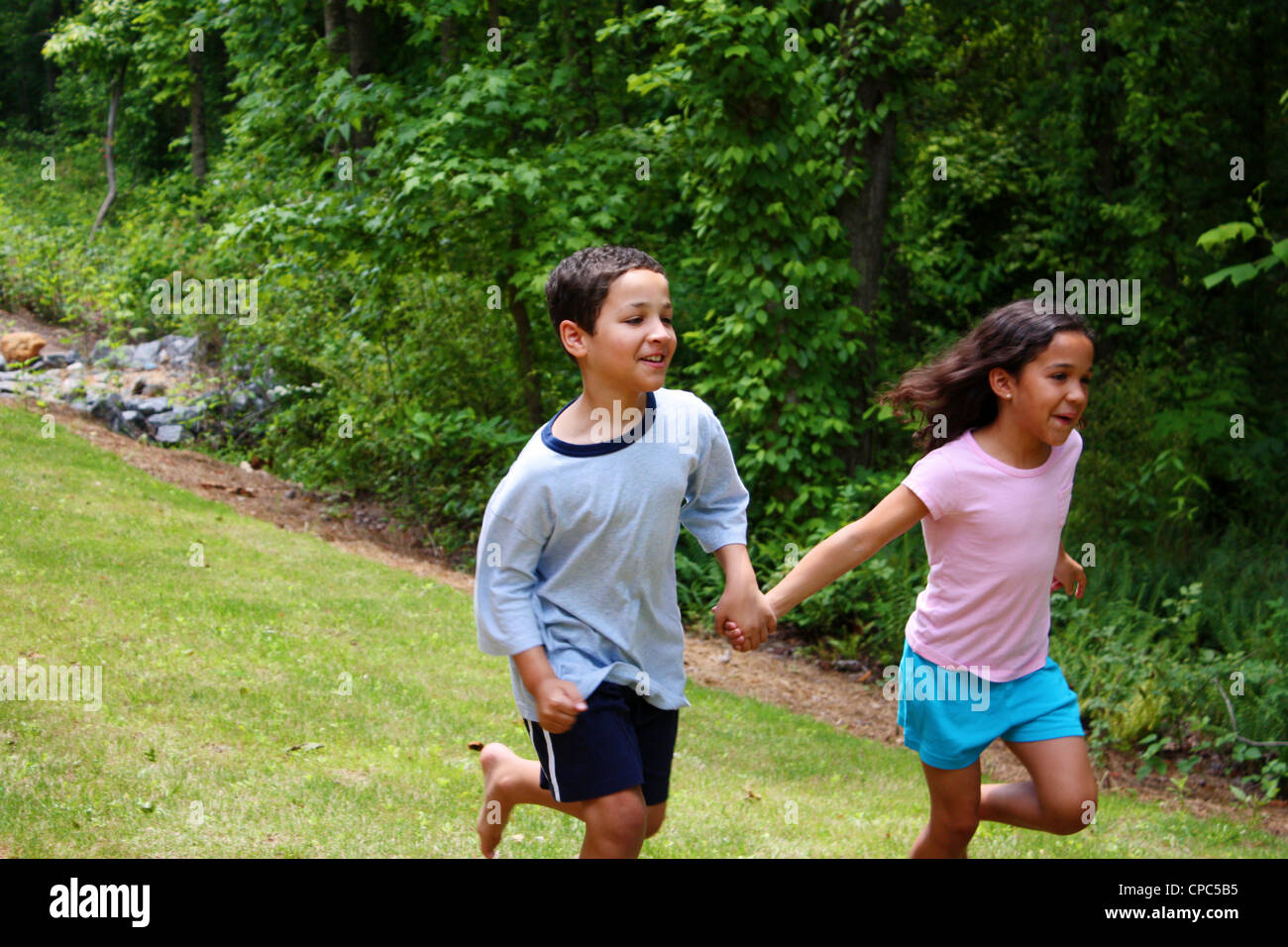 Boy and girl running outside in the grass holding hands Stock Photo - Alamy