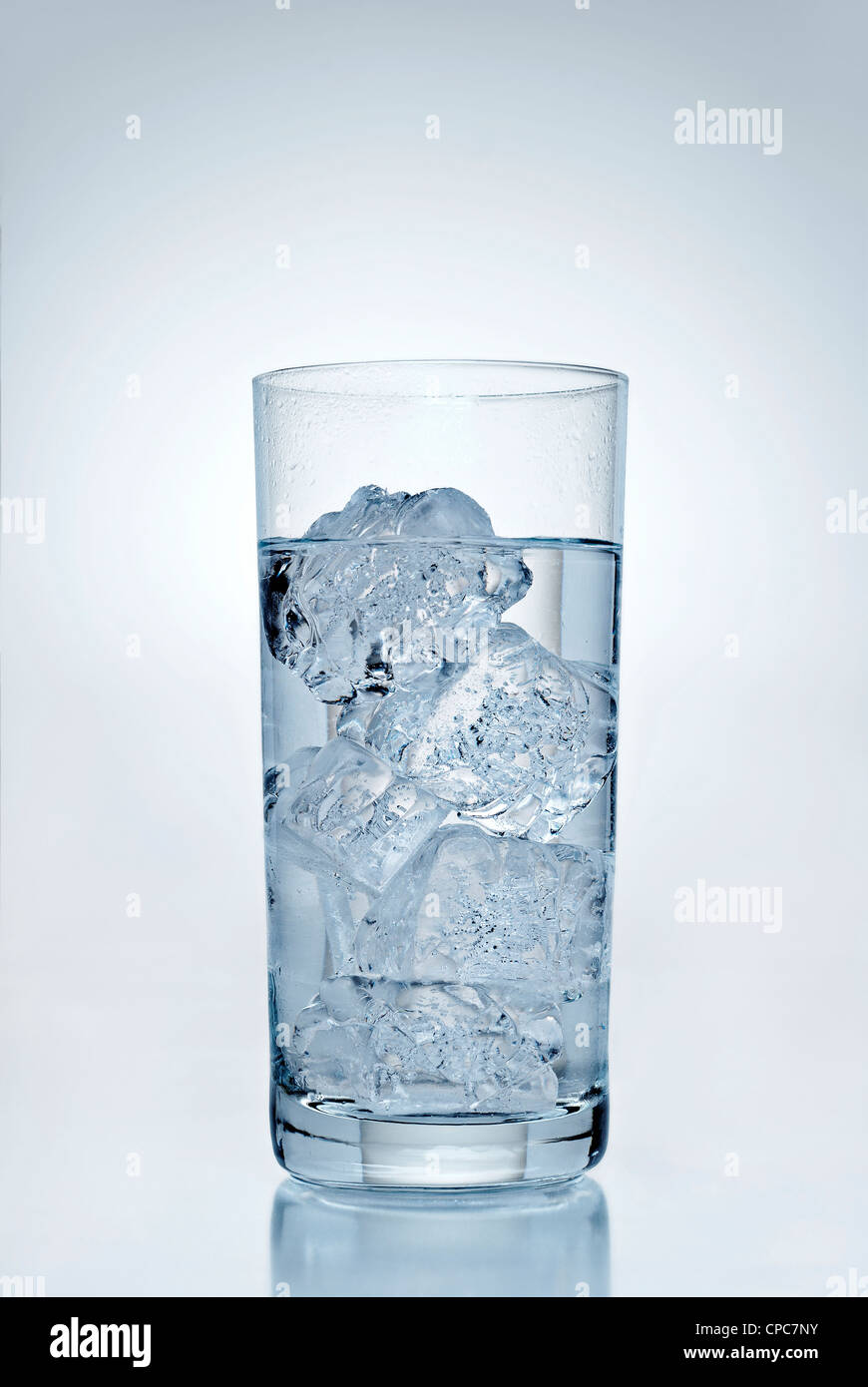 Drink with ice cubes in front of a blue background. Stock Photo