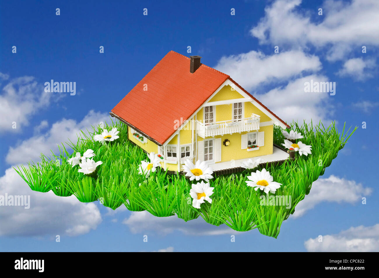 Model house on artificial grass against a blue sky as a symbol of a ...