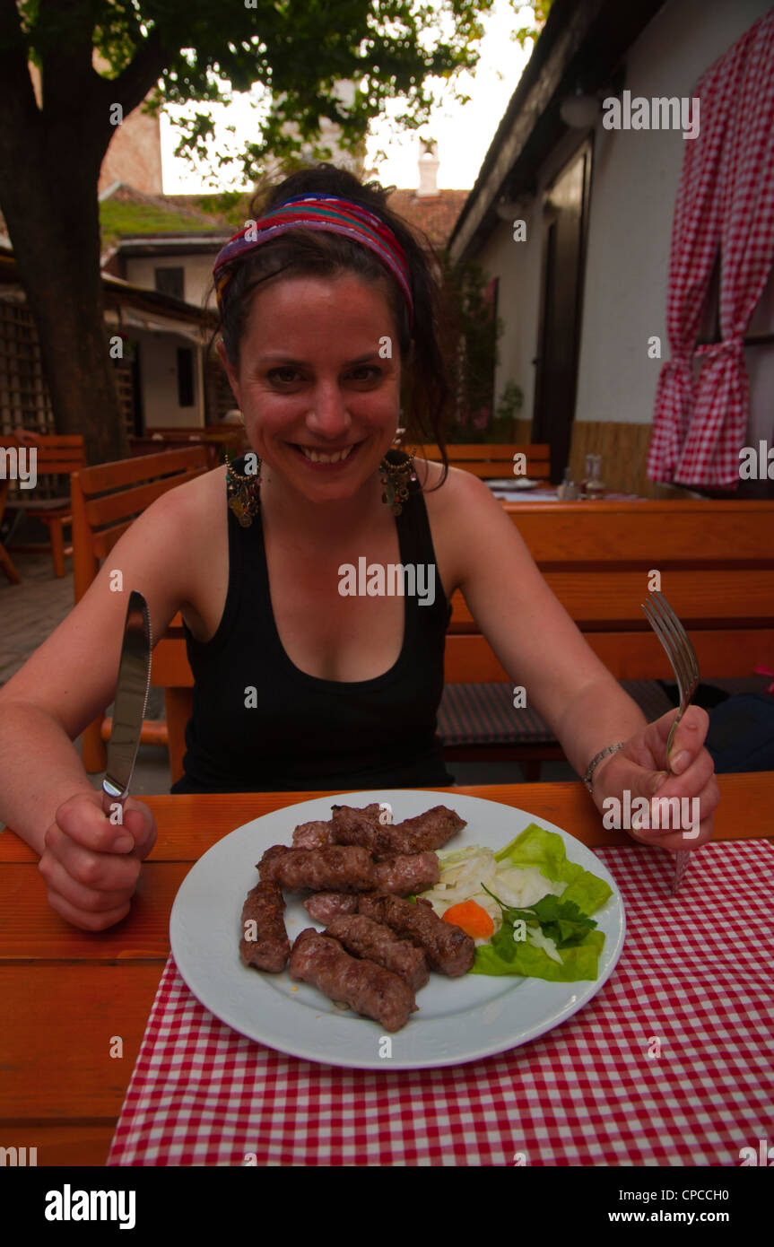Female in her early 30s eating cevapcici traditional meat dish Restaurant ? in Stari Grad the old town Belgrade Serbia Europe Stock Photo