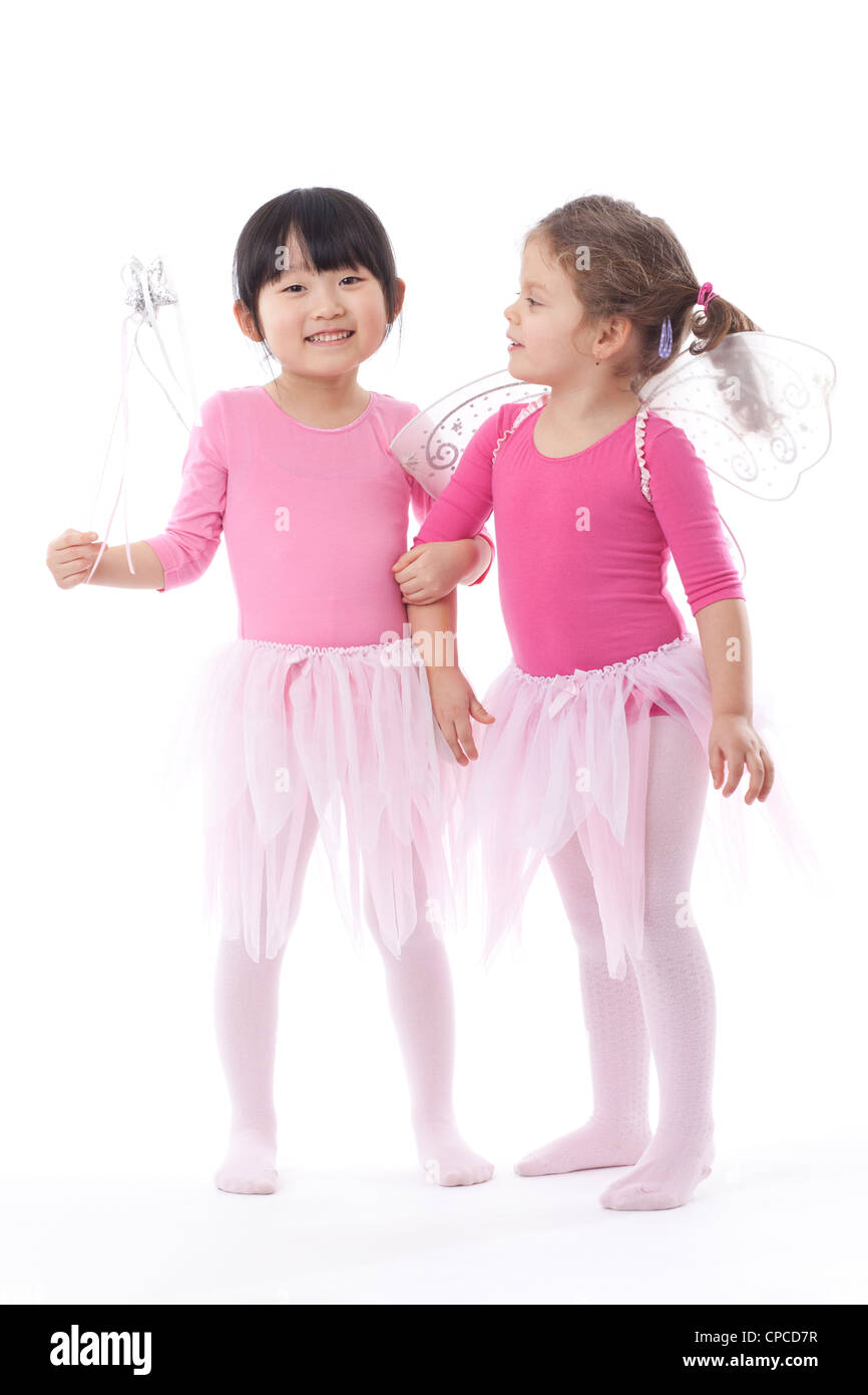 Two young girls wearing pink tutus shot in the studio against a white
