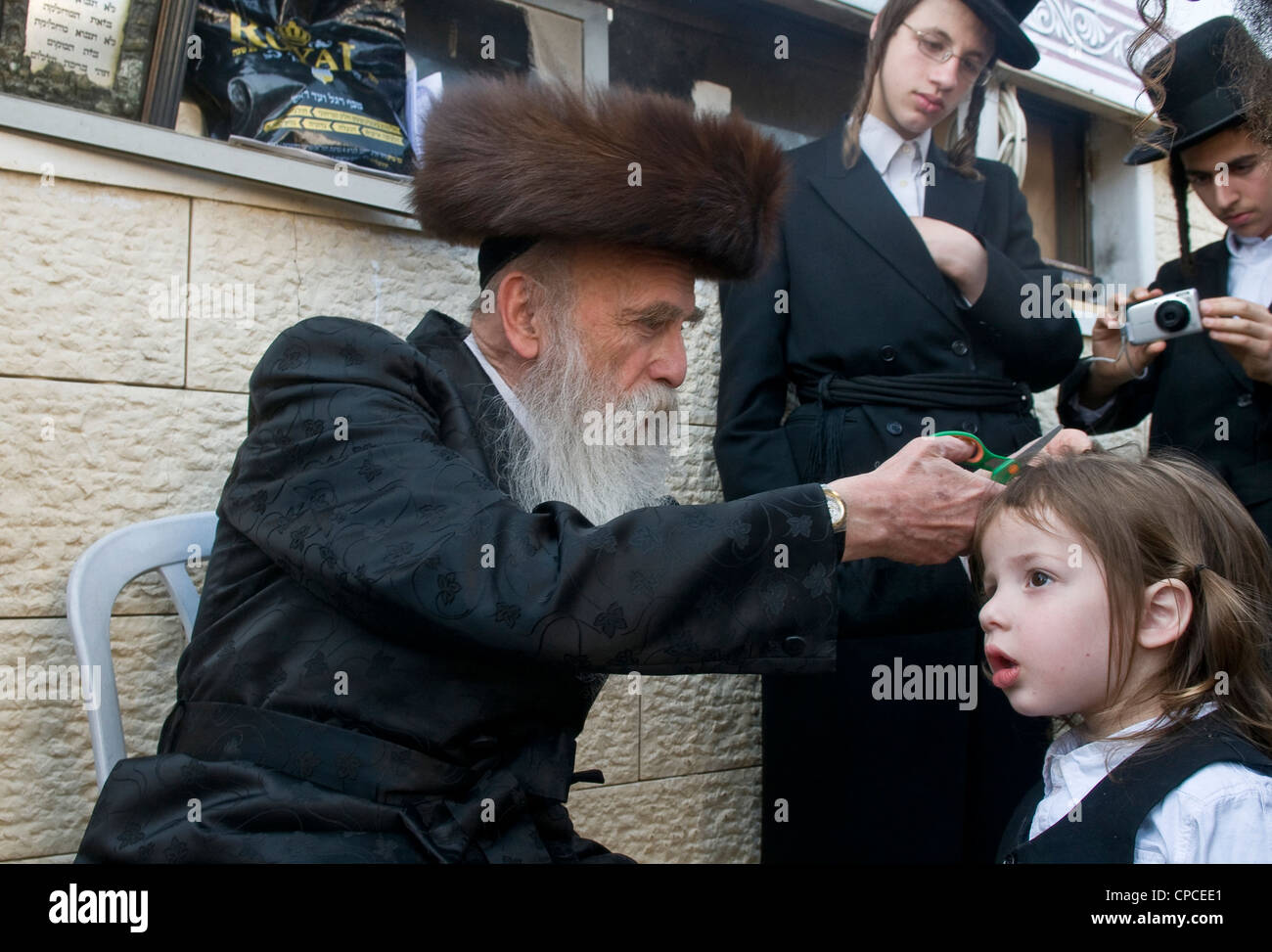 Rabbi cuts child's hair in a Halake ceremony in Bar Yochai tomb in Meron , Israel Stock Photo