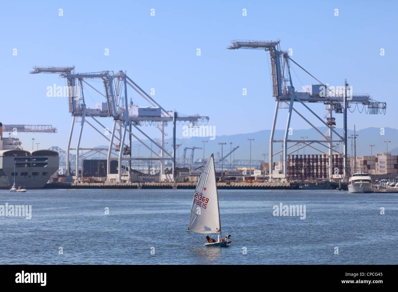 A small sail boat in an industrial harbor Stock Photo