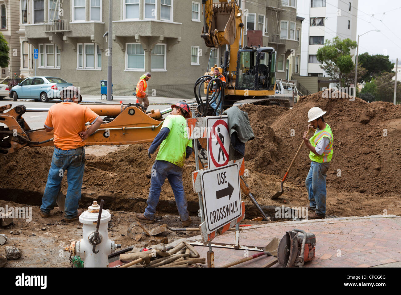 Municipal construction workers and backhoe digging trench Stock Photo