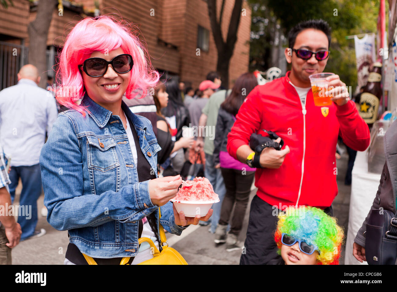 An Asian woman wearing a pink wig at an outdoor festival Stock Photo