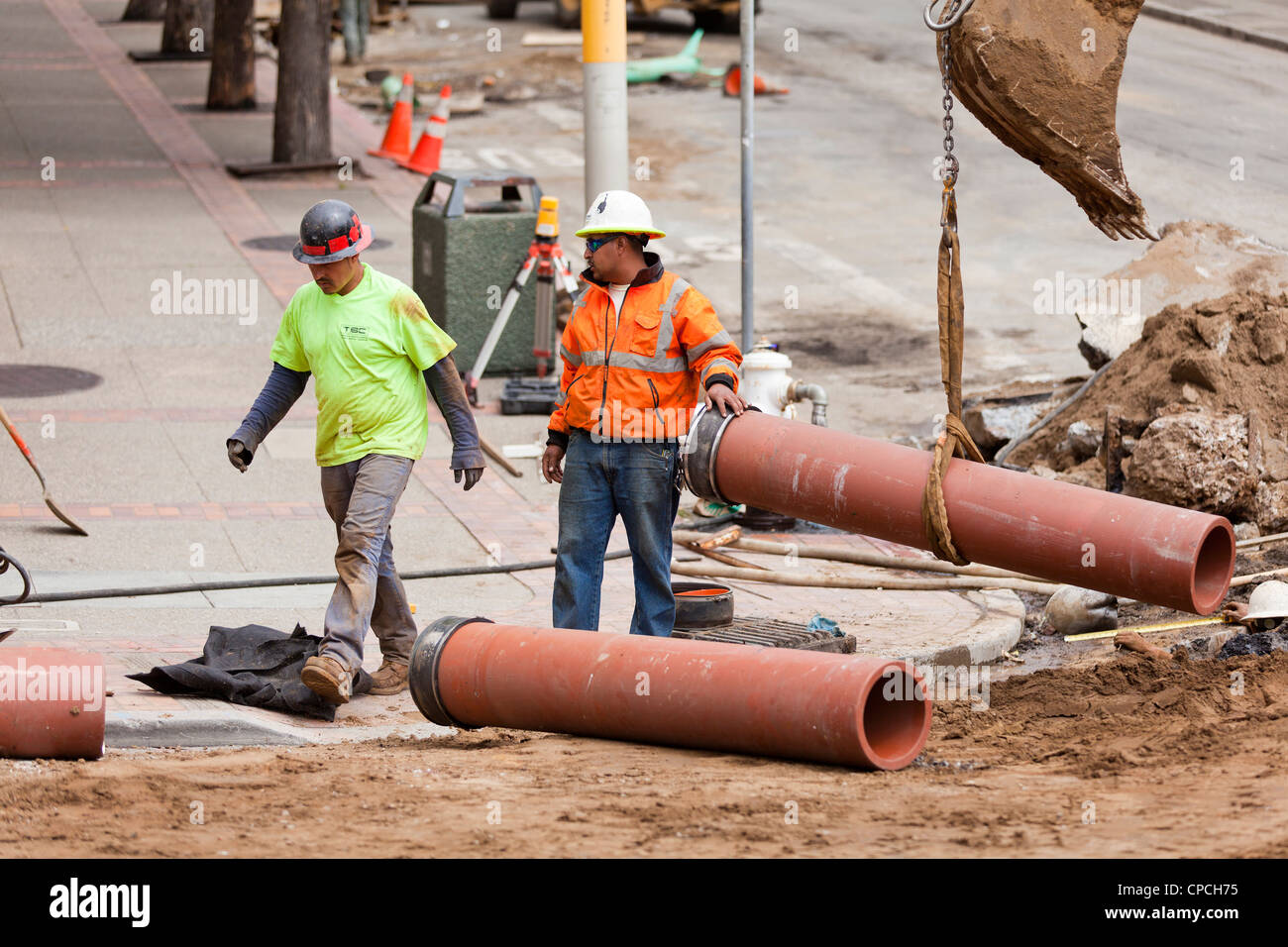 Municipal construction workers installing underground piping Stock