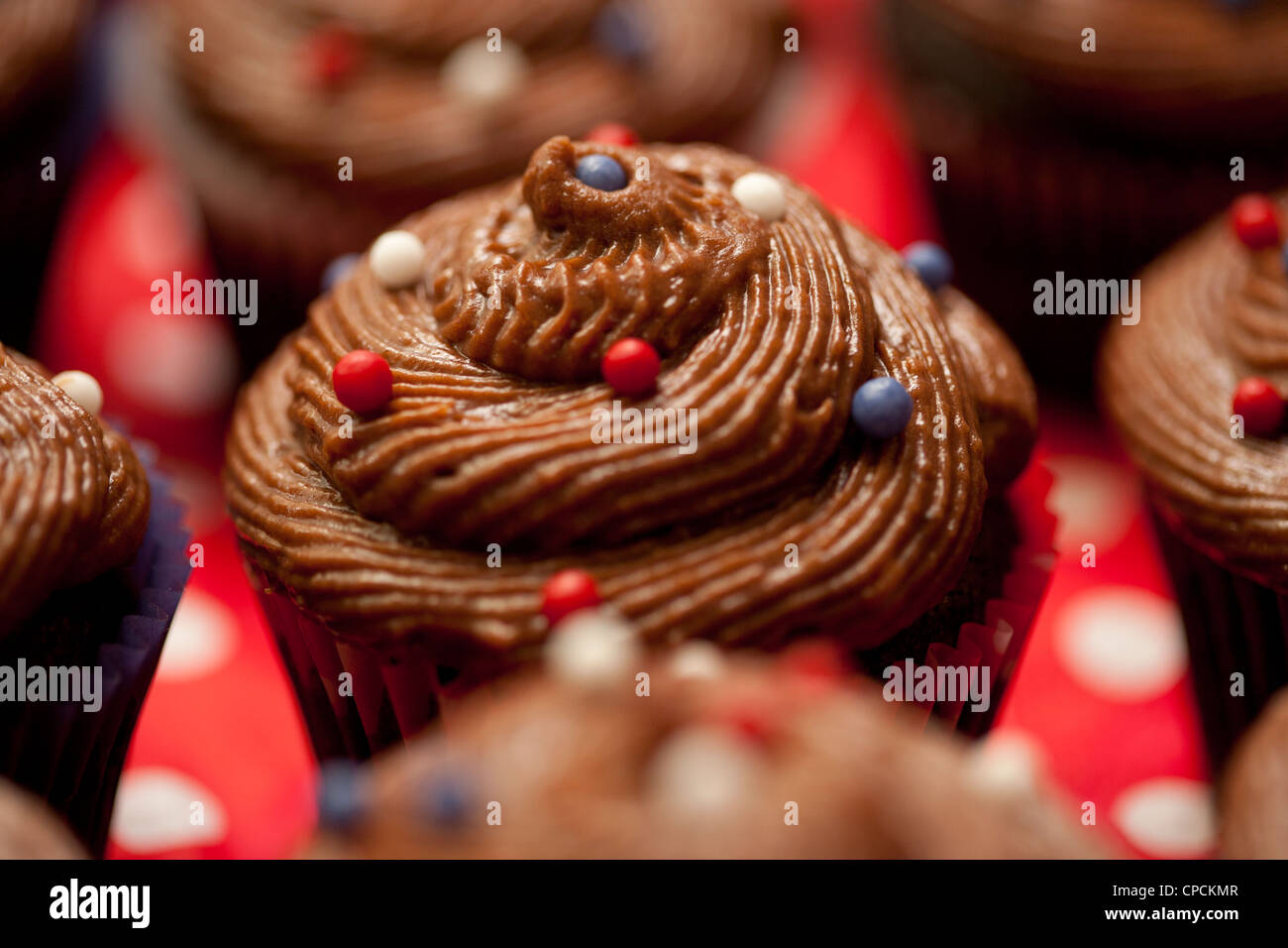 Chocolate piped icing with sugar balls on small cakes Stock Photo