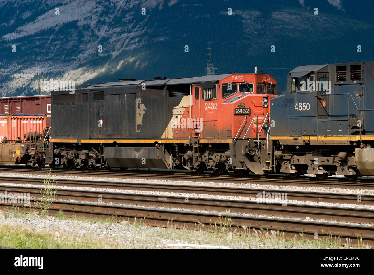 A Canadian National C40-8M locomotive helps pull a train through Jasper rail yard, with a BC Rail locomotive ahead. Stock Photo