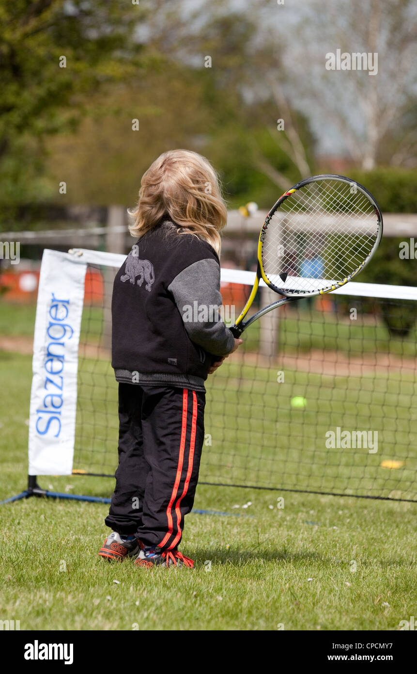 A very young girl having a go at playing tennis, newmarket, Suffolk UK Stock Photo