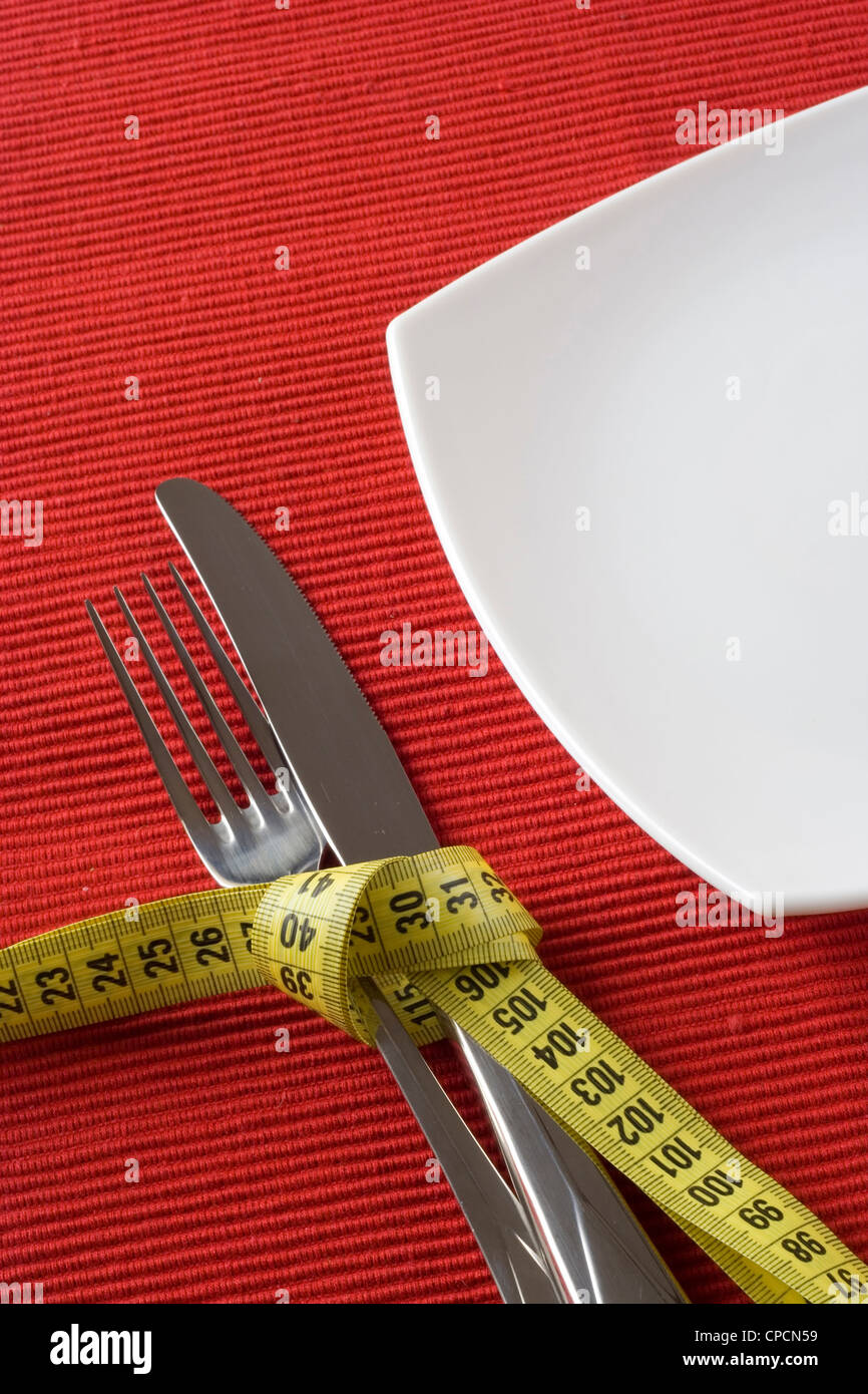 Fork and knife tieup with a measure tape. Conceptual idea of controling obesity. Stock Photo