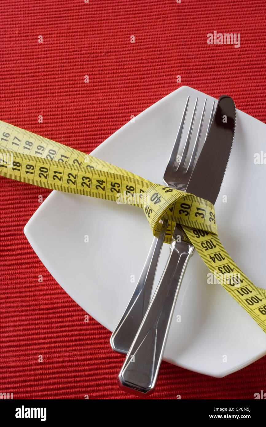Fork and knife tieup with a measure tape. Conceptual idea of controling obesity. (selective and soft focus) Stock Photo
