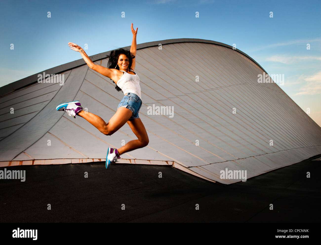 Woman jumping for joy on urban rooftop Stock Photo